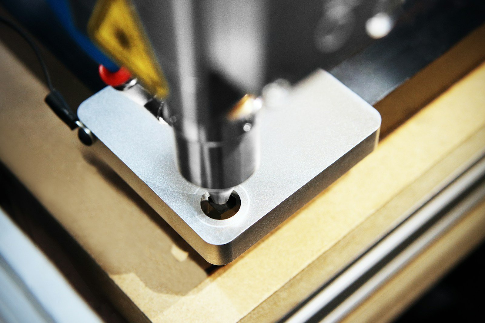 Close-up photograph of a laser head and its metal mounting plate on a CNC machine